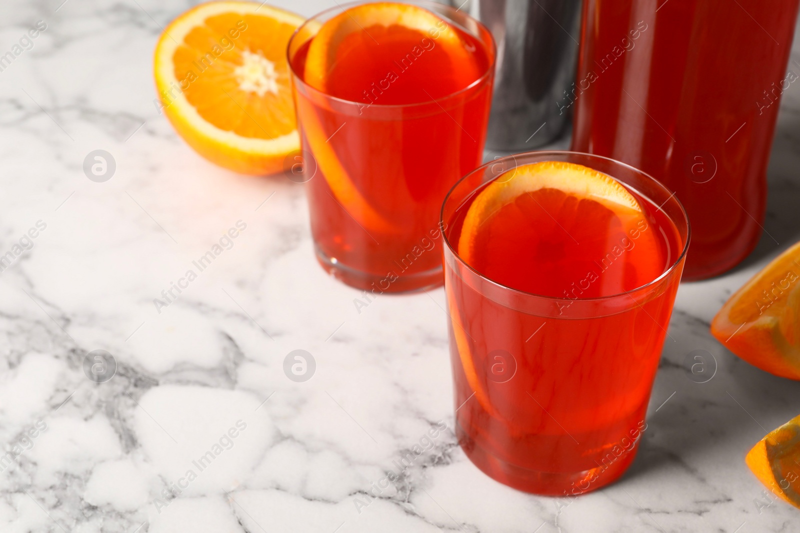 Photo of Aperol spritz cocktail and orange slices in glasses on white marble table, closeup. Space for text