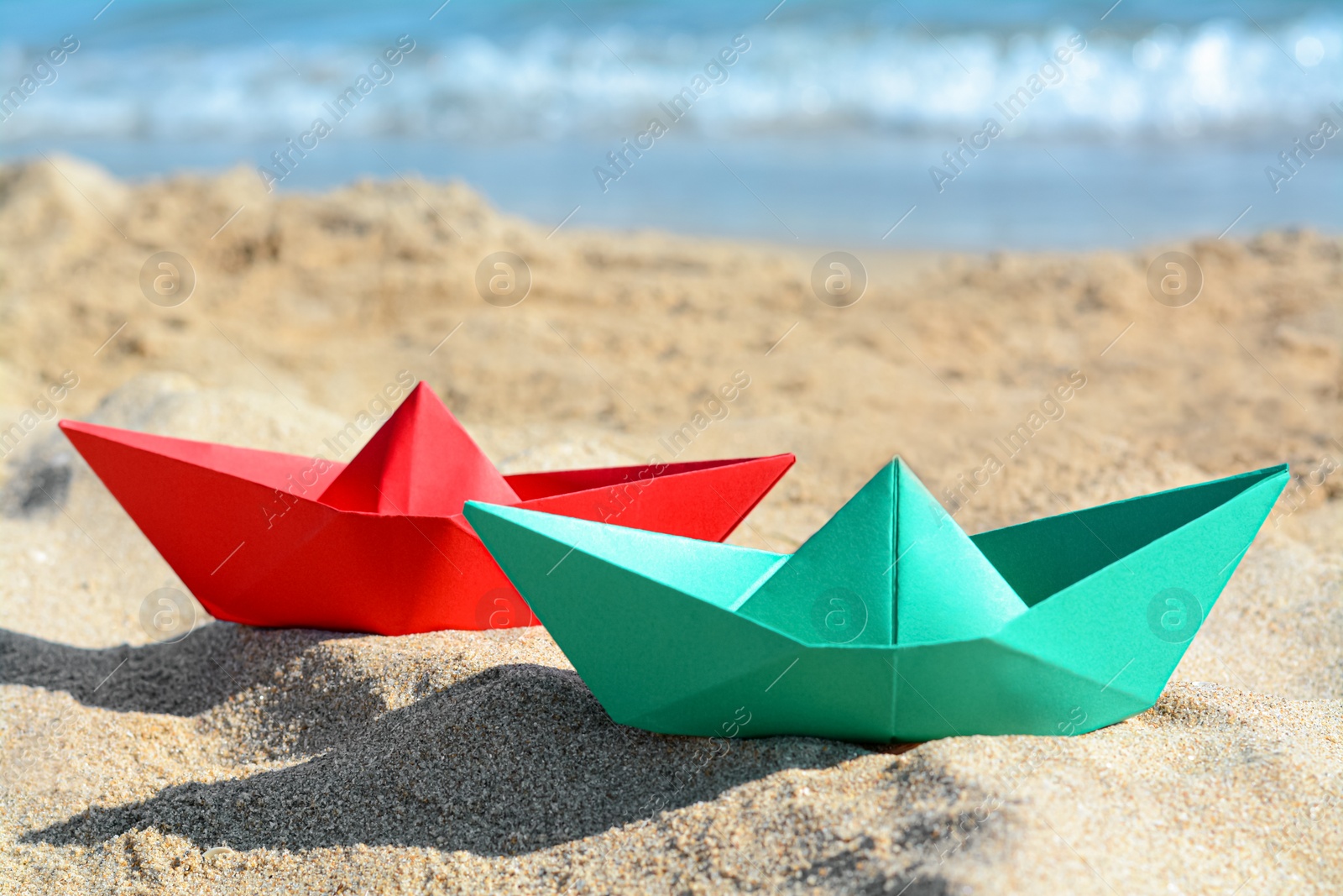 Photo of Two paper boats near sea on sunny day, closeup