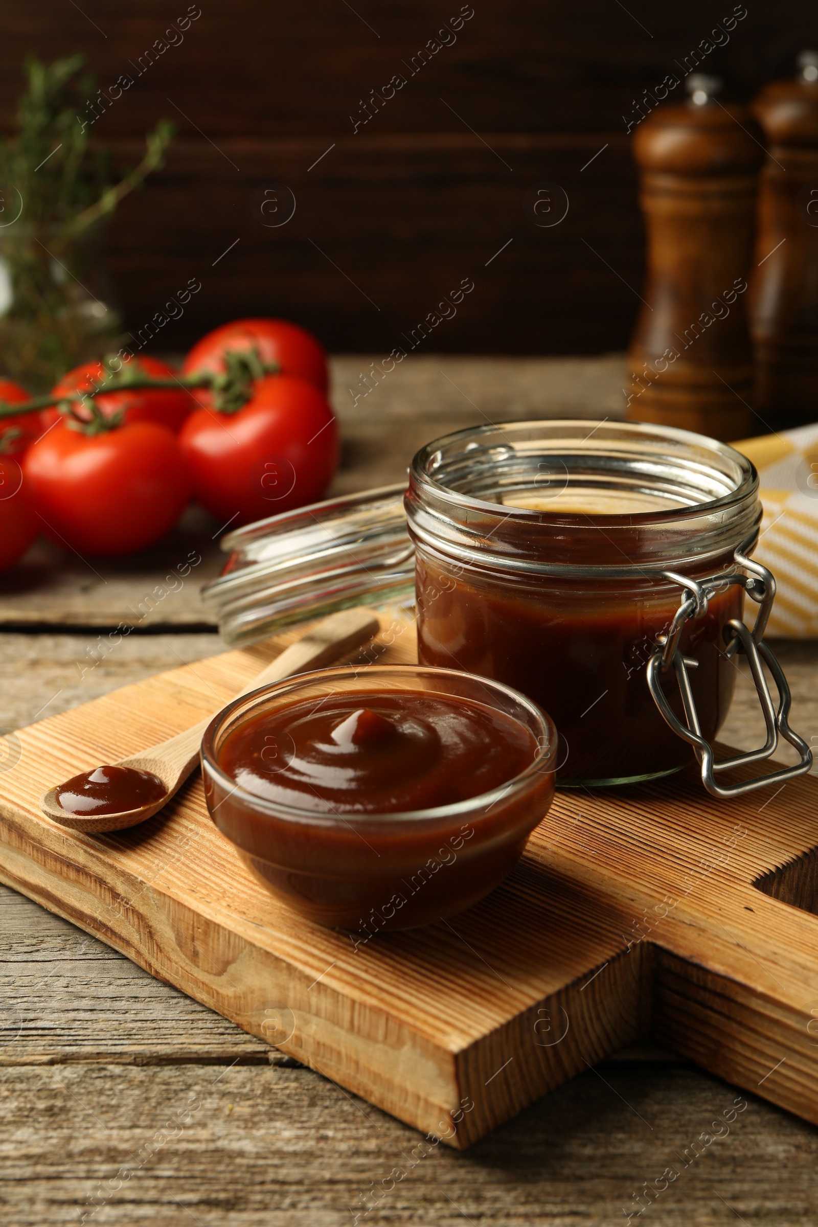 Photo of Tasty barbeque sauce in bowl, jar and spoon on wooden table