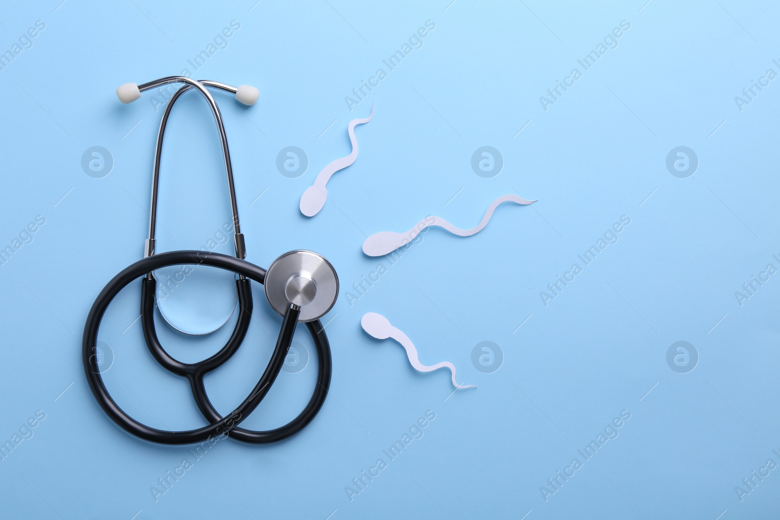 Photo of Reproductive medicine. Figures of sperm cells and stethoscope on light blue background, flat lay with space for text