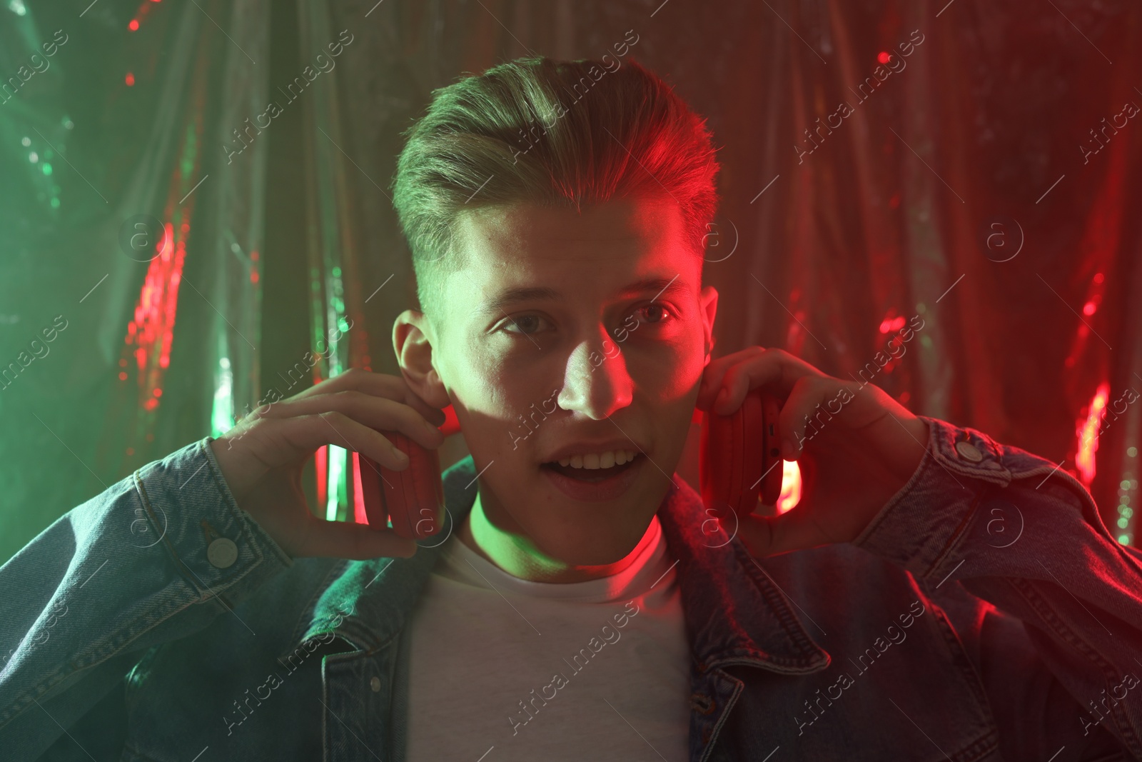 Photo of Young man with headphones in neon lights