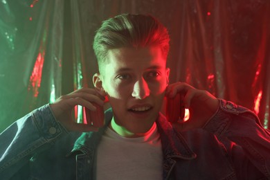 Photo of Young man with headphones in neon lights