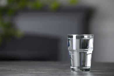 Photo of Glass of clean water on grey table indoors, space for text