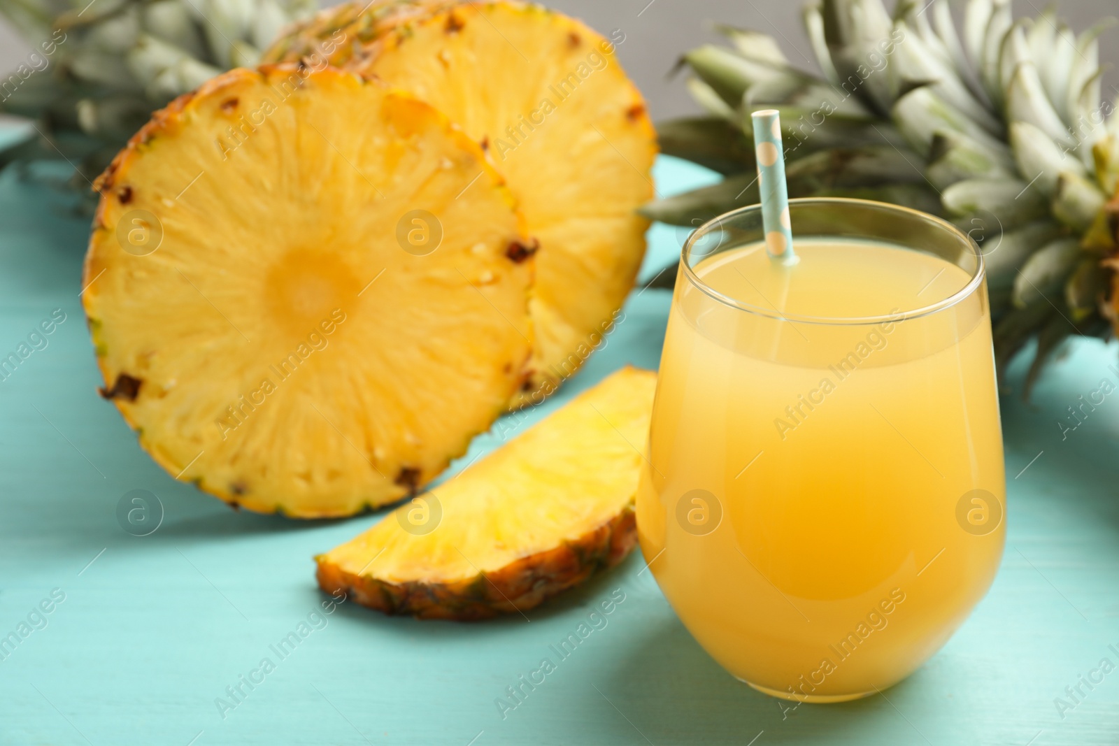 Photo of Delicious pineapple juice and fresh fruit on light blue wooden table