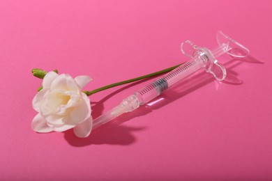 Photo of Cosmetology. Medical syringe and freesia flower on pink background