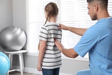 Photo of Orthopedist examining child's back in clinic. Scoliosis treatment