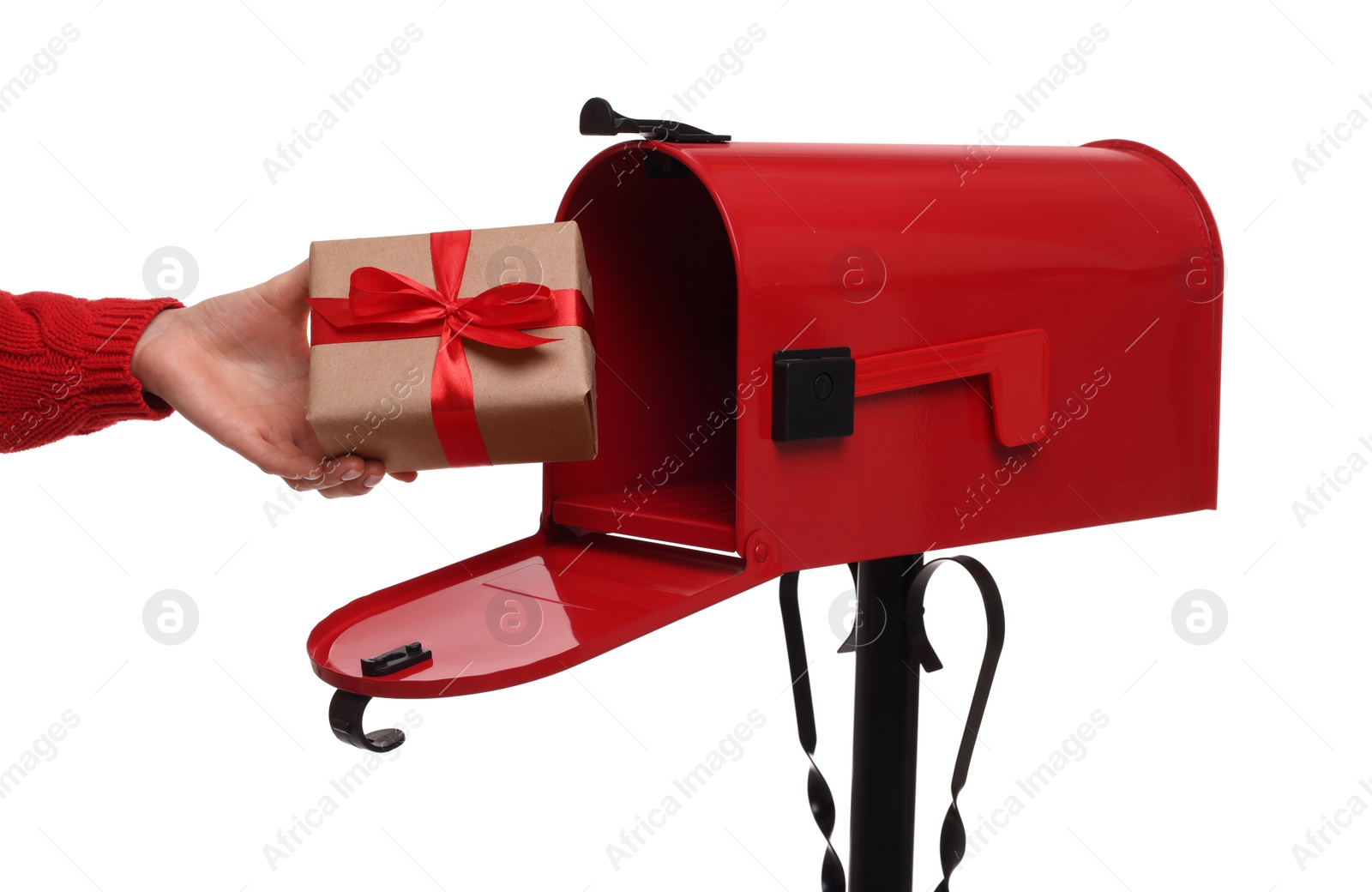 Photo of Woman putting Christmas gift into mailbox on white background, closeup. Sending present by mail