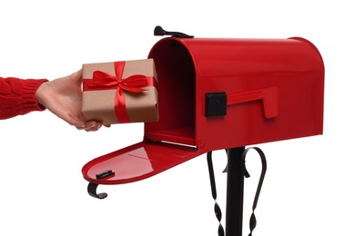 Photo of Woman putting Christmas gift into mailbox on white background, closeup. Sending present by mail