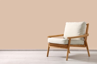 Photo of Stylish armchair near beige wall indoors, space for text