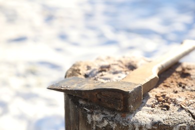 Metal axe on wooden log outdoors on sunny winter day, closeup. Space for text