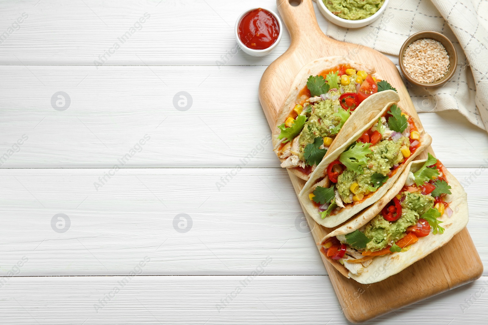 Photo of Delicious tacos with guacamole, meat and vegetables served on white wooden table, flat lay. Space for text