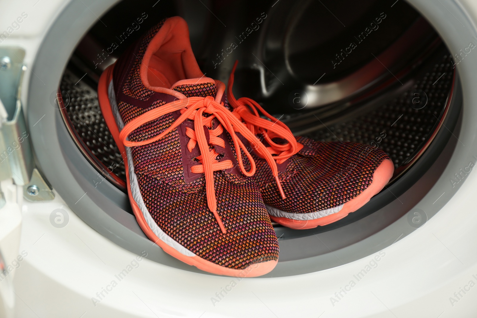 Photo of Clean sports shoes in washing machine drum, closeup
