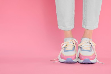 Photo of Woman wearing new stylish sneakers on pink background, closeup. Space for text