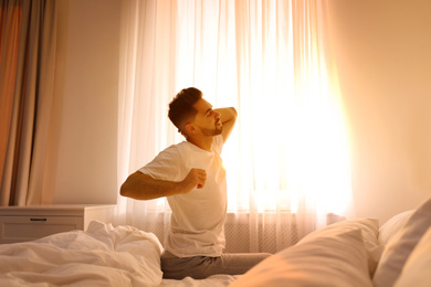 Photo of Young man stretching on bed at home. Lazy morning