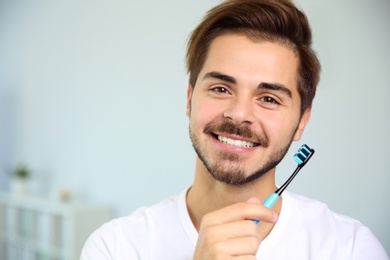 Photo of Portrait of young man with toothbrush on blurred background. Space for text