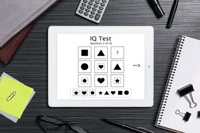 Image of Modern tablet with IQ test on black wooden table, flat lay 