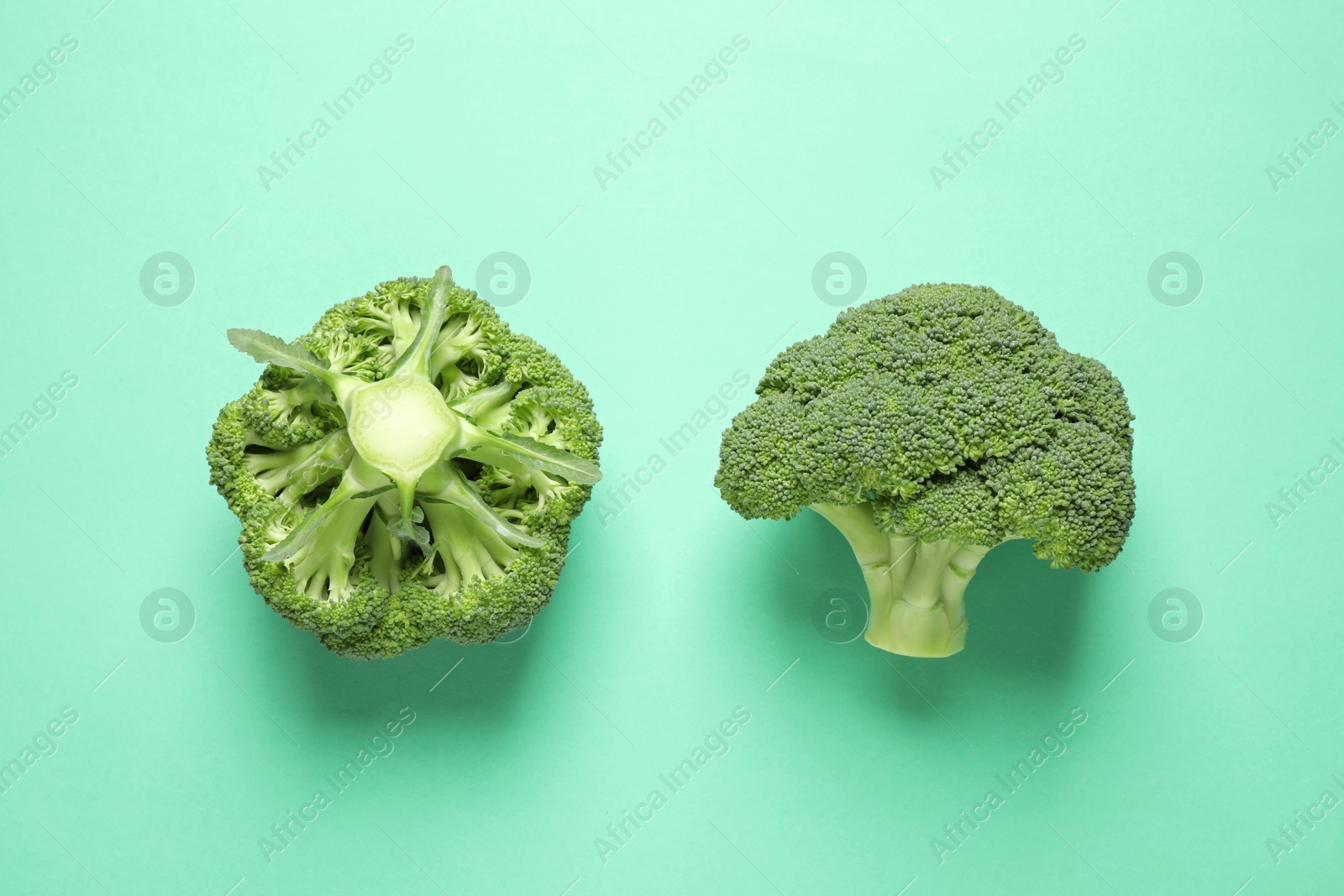 Photo of Fresh tasty broccoli on turquoise background, flat lay