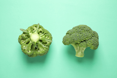 Photo of Fresh tasty broccoli on turquoise background, flat lay