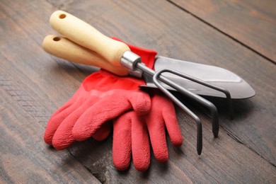 Gardening gloves, trowel and rake on wooden table