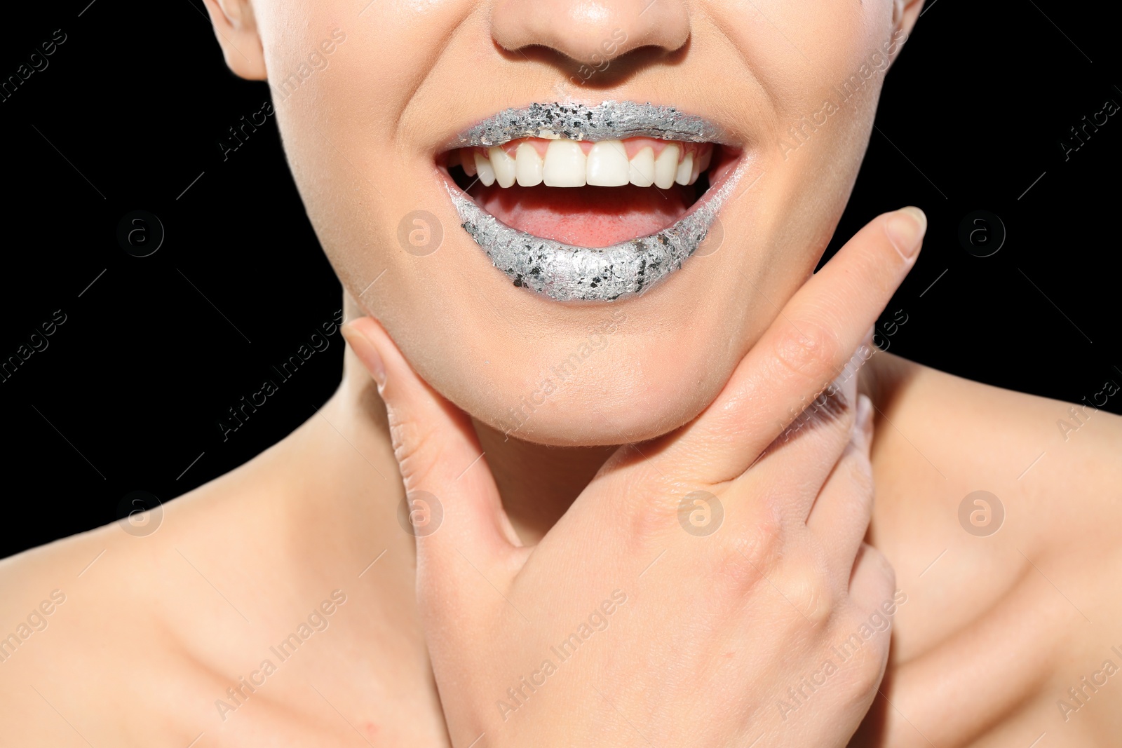 Photo of Beautiful young model with silver lips makeup on black background