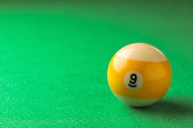 Photo of Billiard ball with number 9 on green table, space for text