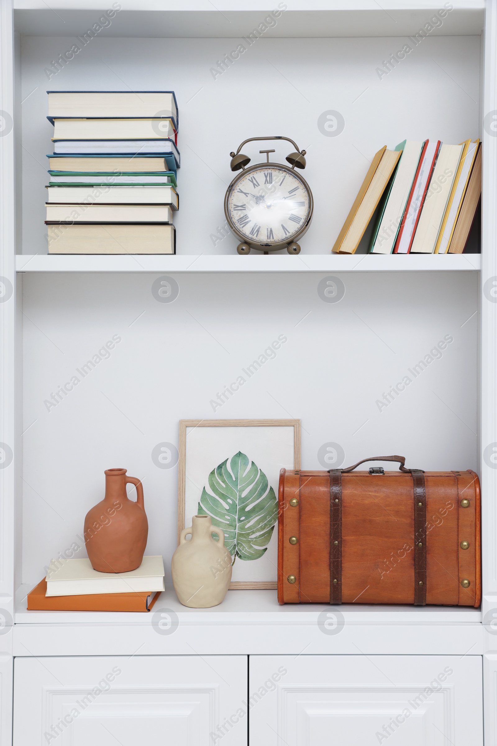 Photo of Books and different decorative elements on shelving unit indoors