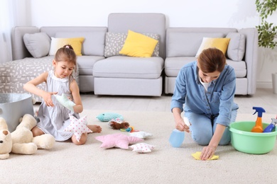 Housewife and daughter cleaning room together