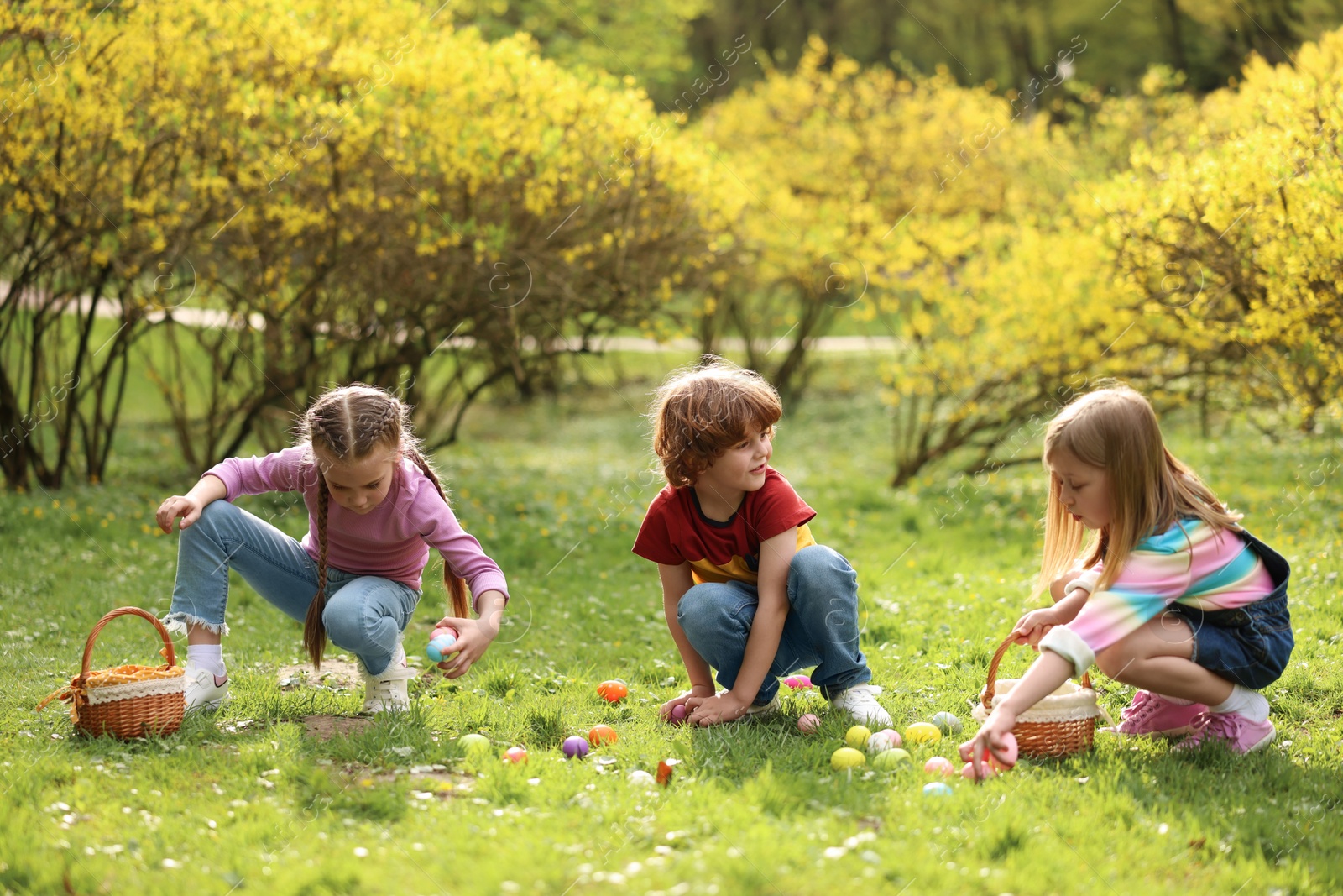 Photo of Easter celebration. Cute little children hunting eggs outdoors