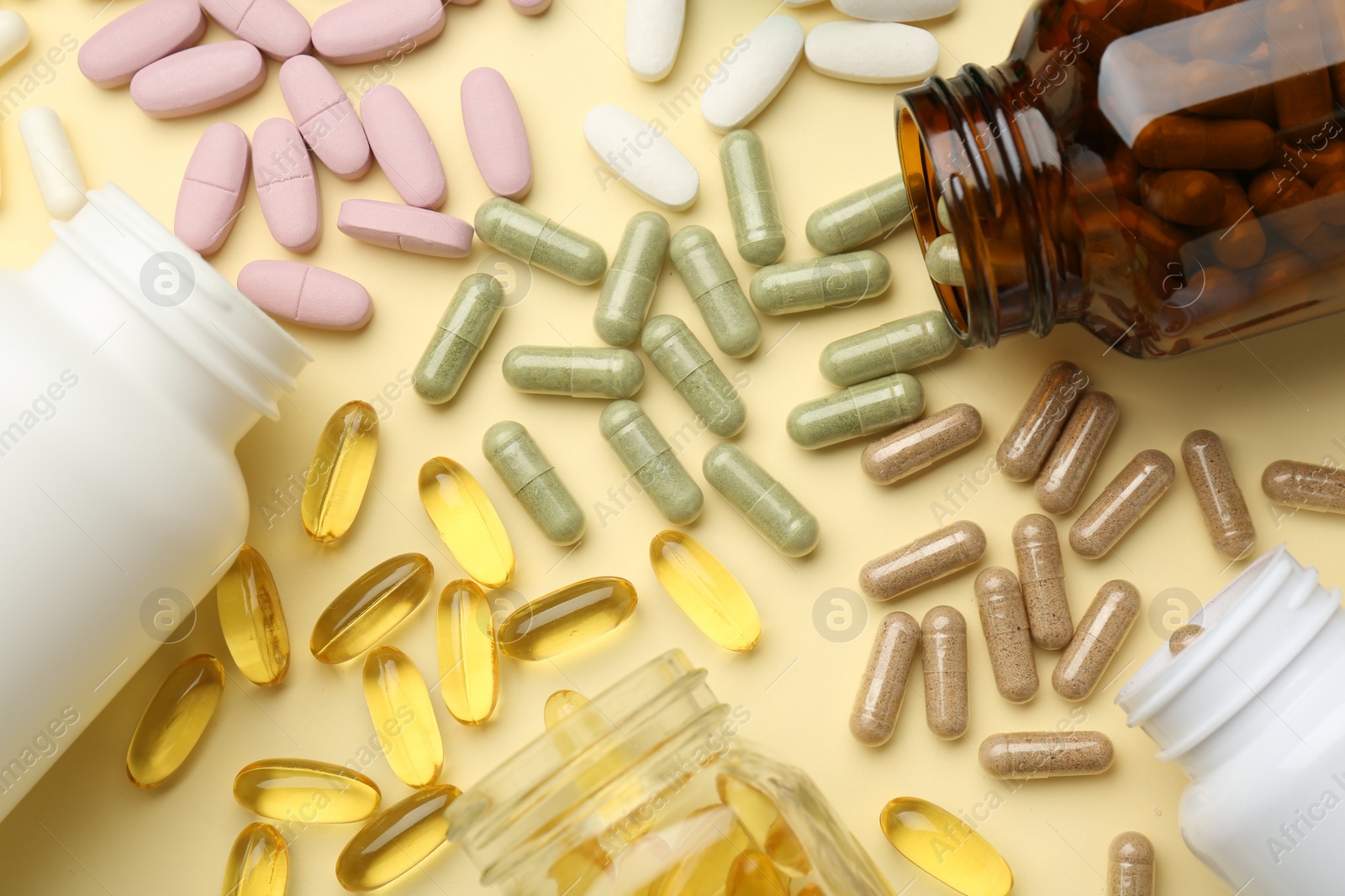 Photo of Many different vitamin pills and bottles on beige background, flat lay