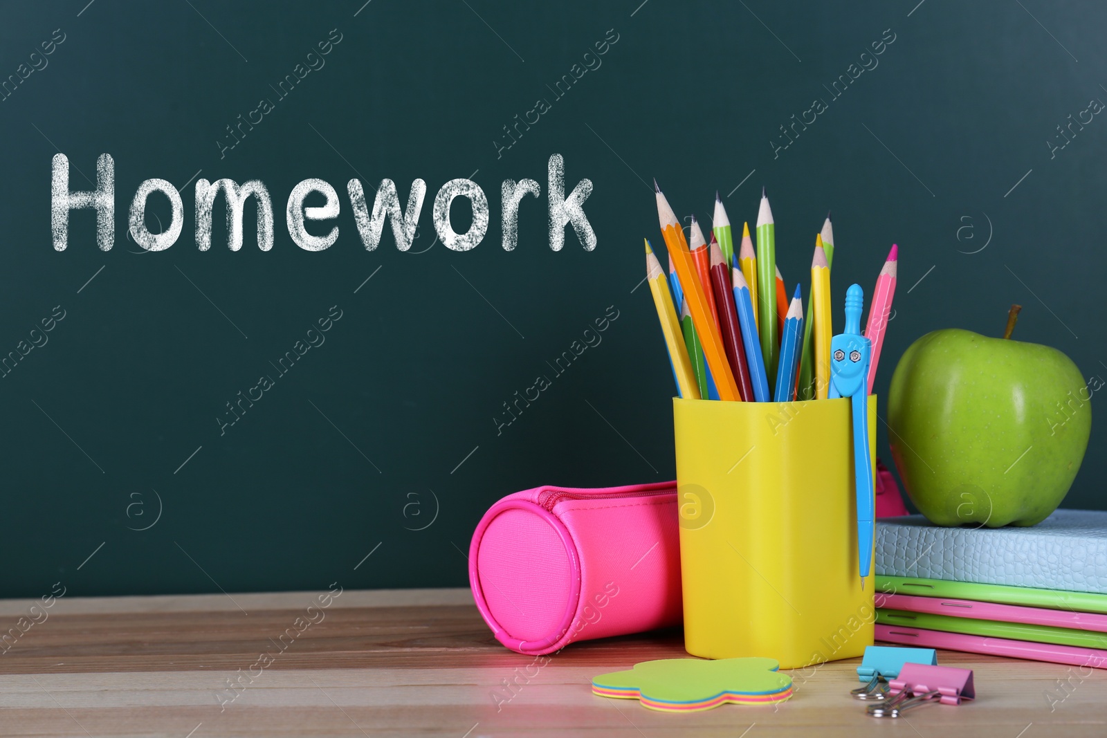 Image of Composition with stationery and apple on table near chalkboard. Doing homework