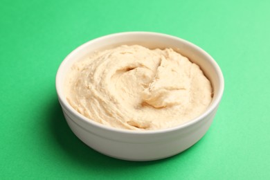 Photo of Bowl of tasty hummus on green background