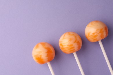 Photo of Tasty lollipops on violet background, flat lay. Space for text