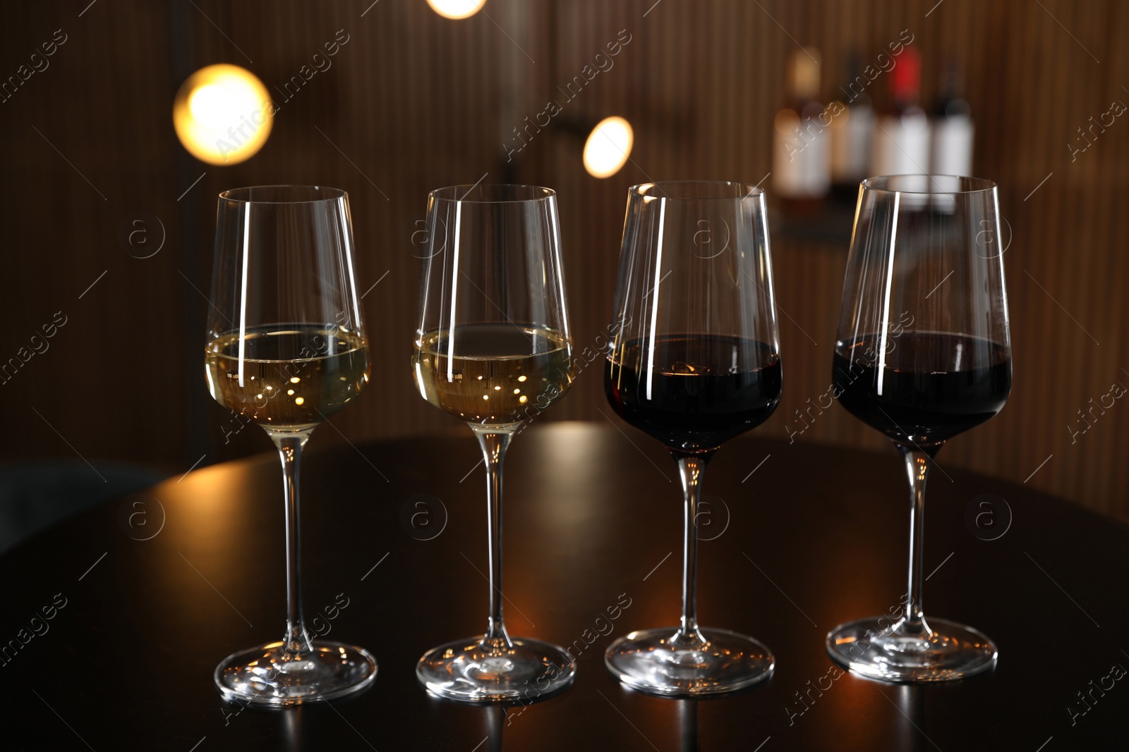 Photo of Glasses of different wines on table against blurred background