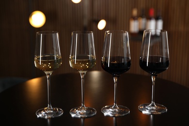 Glasses of different wines on table against blurred background