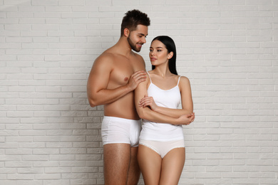 Photo of Young couple in white underwear near brick wall