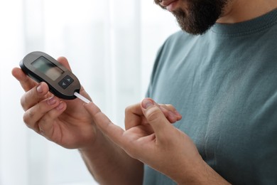 Diabetes test. Man checking blood sugar level with glucometer at home, closeup