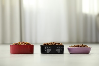 Photo of Dry food in pet bowls on floor indoors, space for text