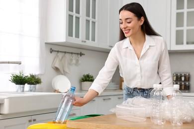 Photo of Smiling woman separating garbage in kitchen. Space for text