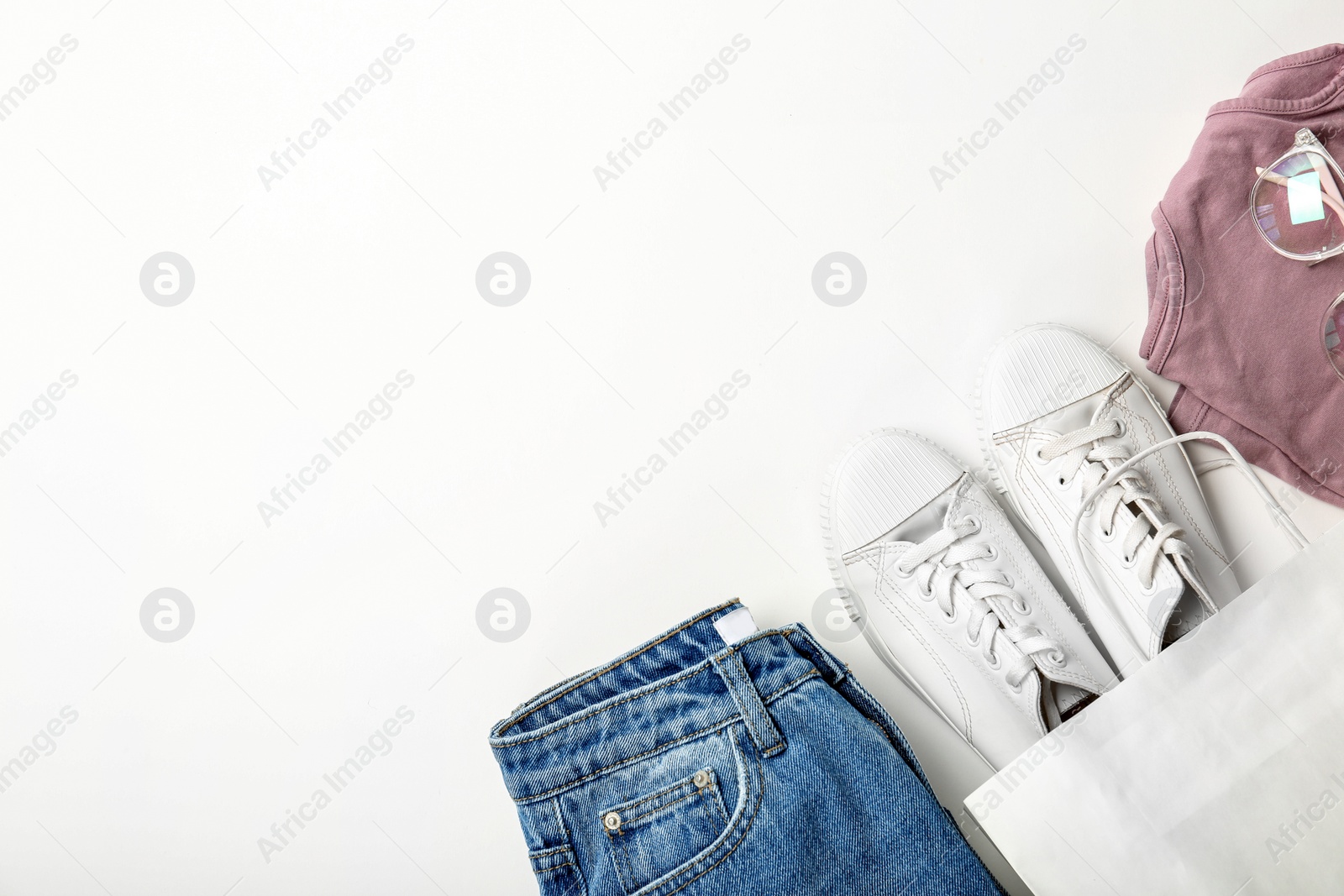 Photo of Stylish flat lay composition with shopping bag and clothing on white background