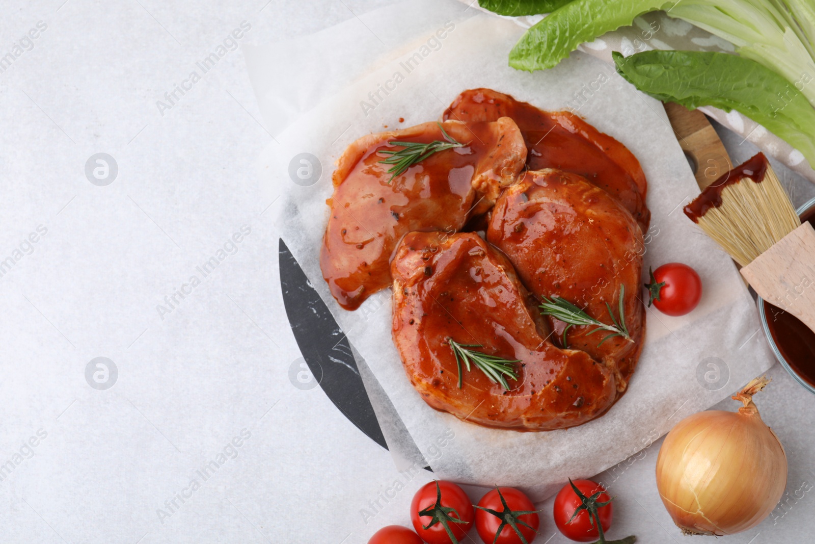 Photo of Flat lay composition with raw marinated meat, products and basting brush on light table. Space for text