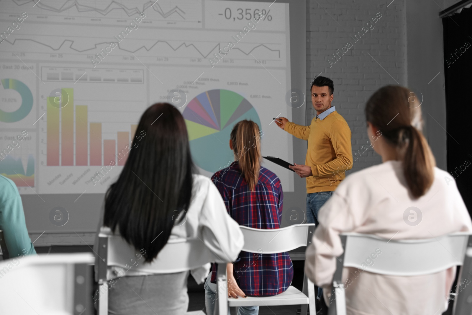 Photo of Male business trainer giving lecture in conference room with projection screen