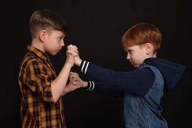 Two boys fighting on black background. Children's bullying