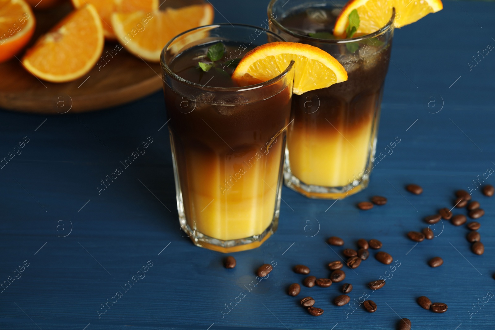 Photo of Tasty refreshing drink with coffee and orange juice on blue wooden table