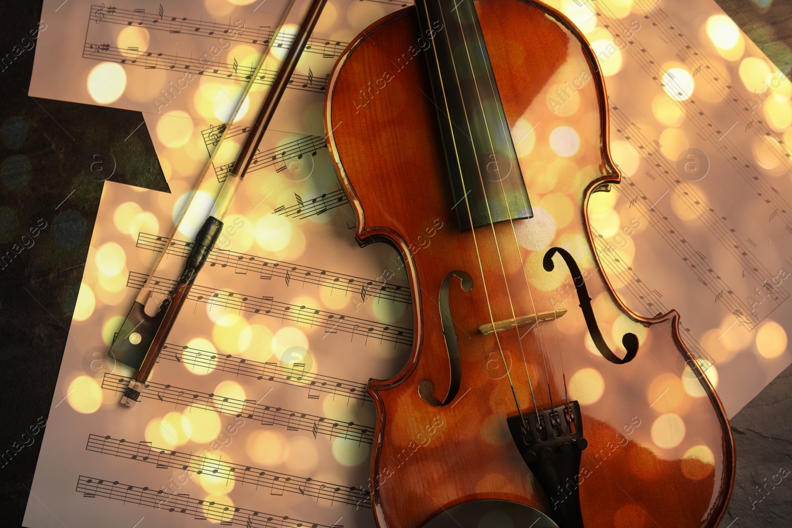 Image of Christmas and New Year music. Violin and music sheets on black background, bokeh effect