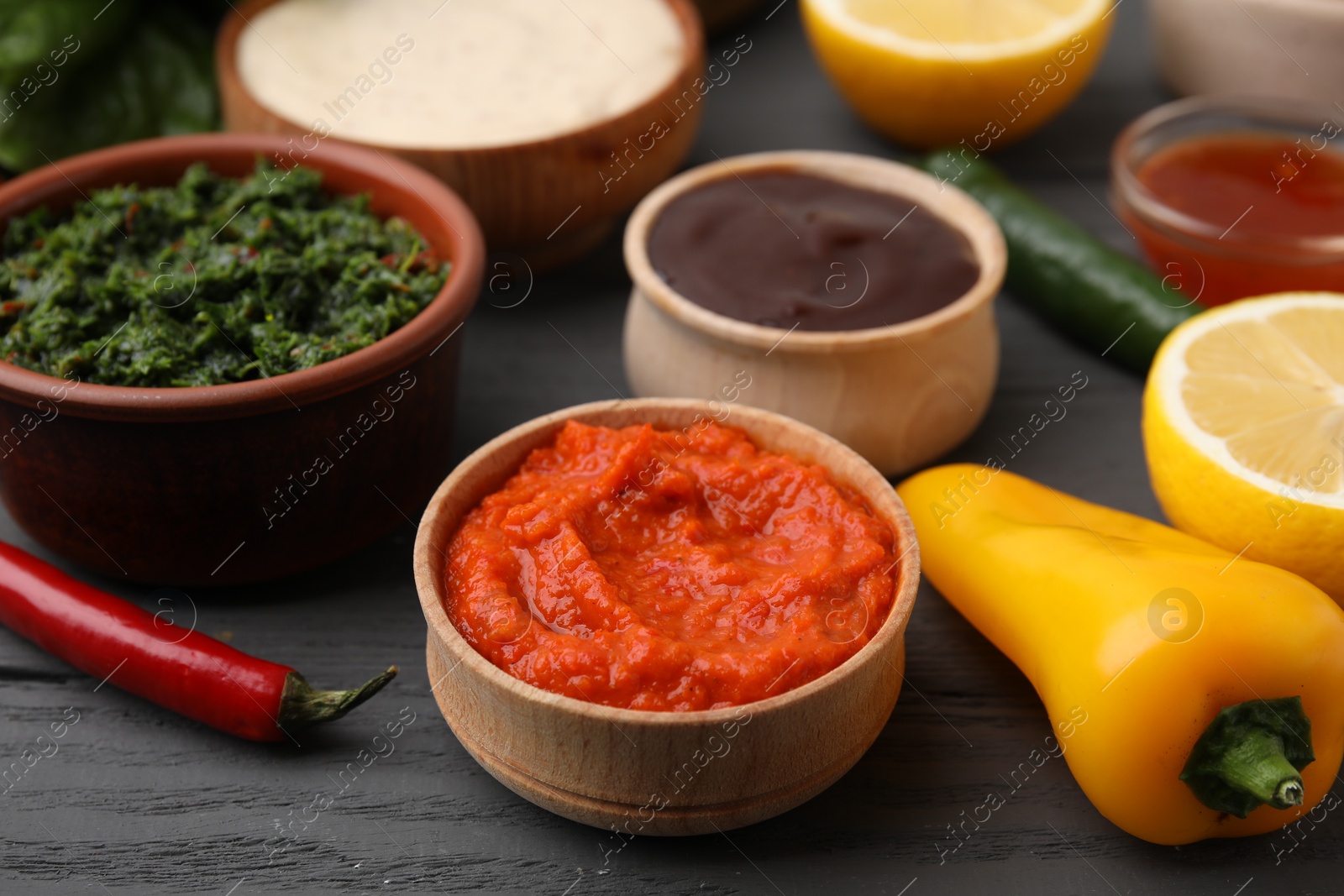 Photo of Fresh marinades in bowls and ingredients on grey wooden table, closeup