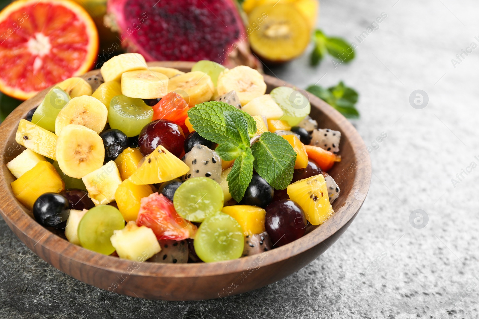 Photo of Delicious exotic fruit salad on grey table, closeup