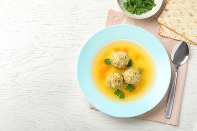 Photo of Flat lay composition with Jewish matzoh balls soup on white wooden table. Space for text