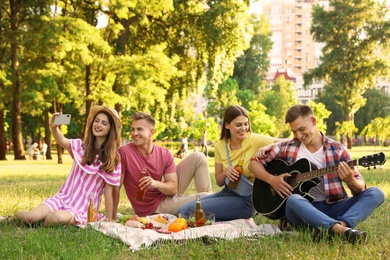 Photo of Young people enjoying picnic in park on summer day