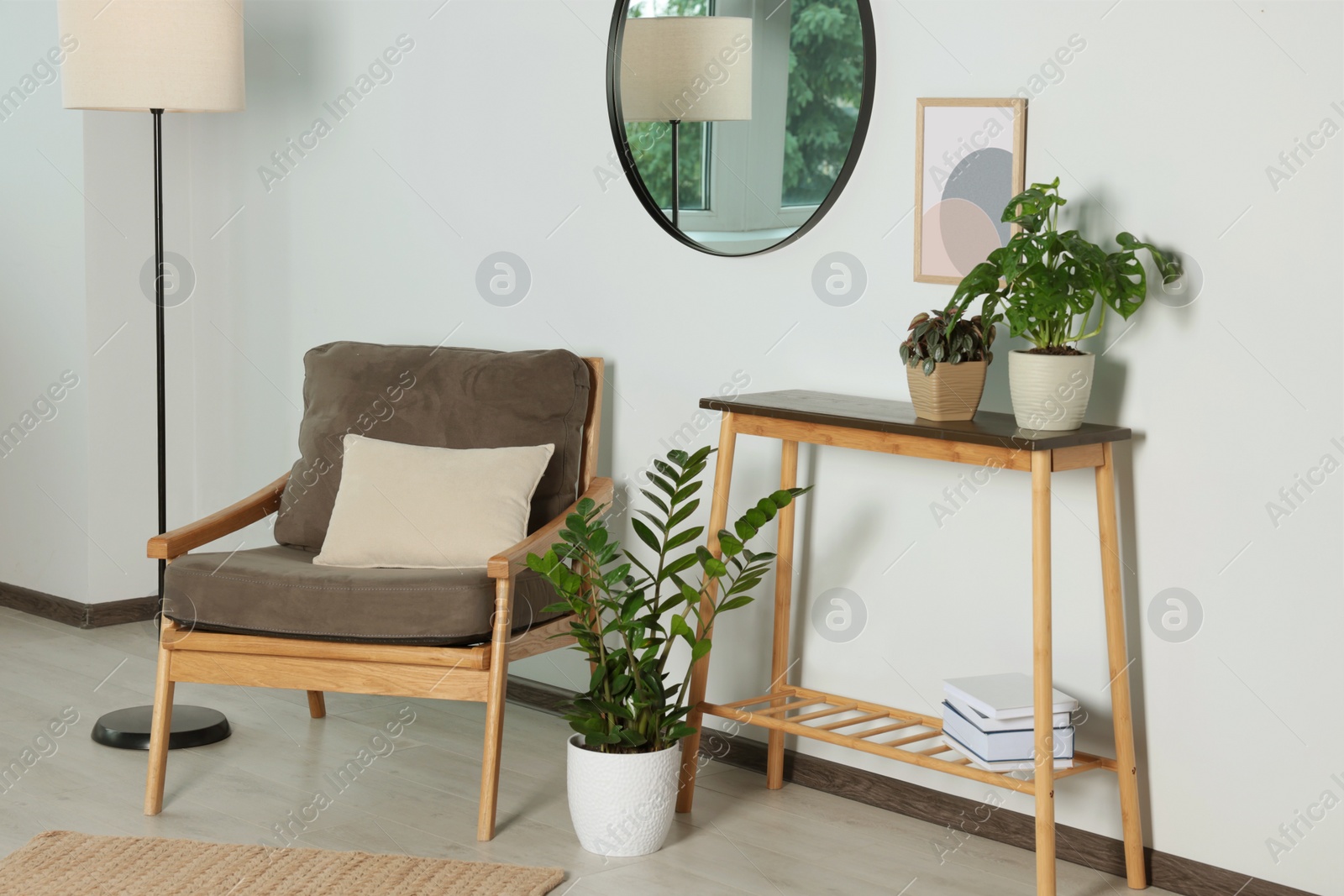 Photo of Stylish living room interior with wooden furniture, houseplants and round mirror on white wall