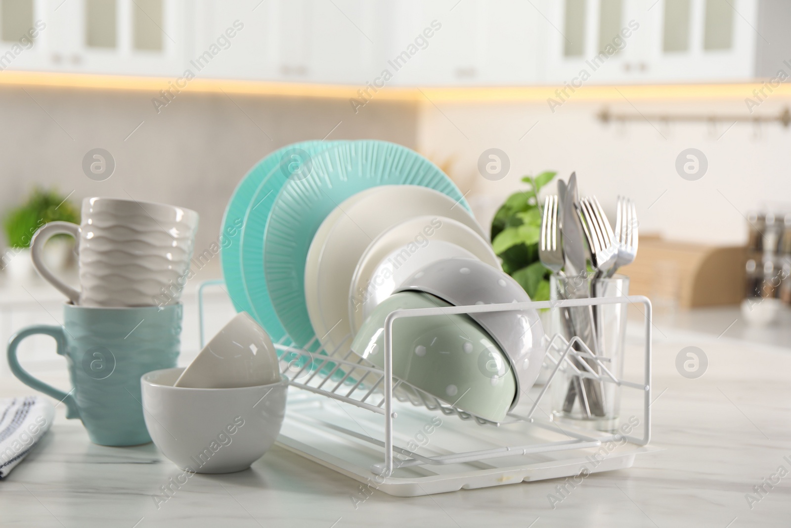 Photo of Many different clean dishware, cups and cutlery on white marble table in kitchen